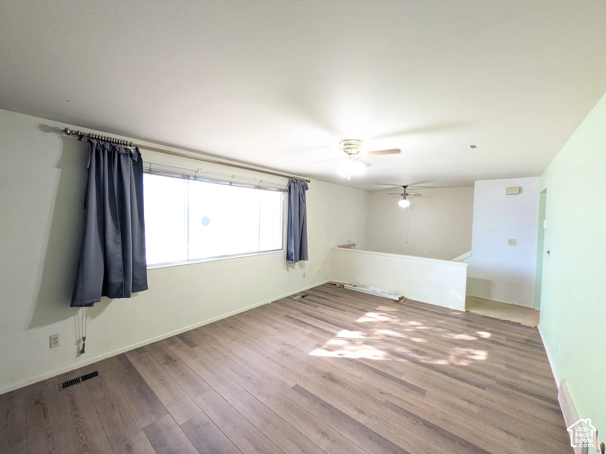 Wood-finish flooring, large window, ceiling fan, and a half-wall partition