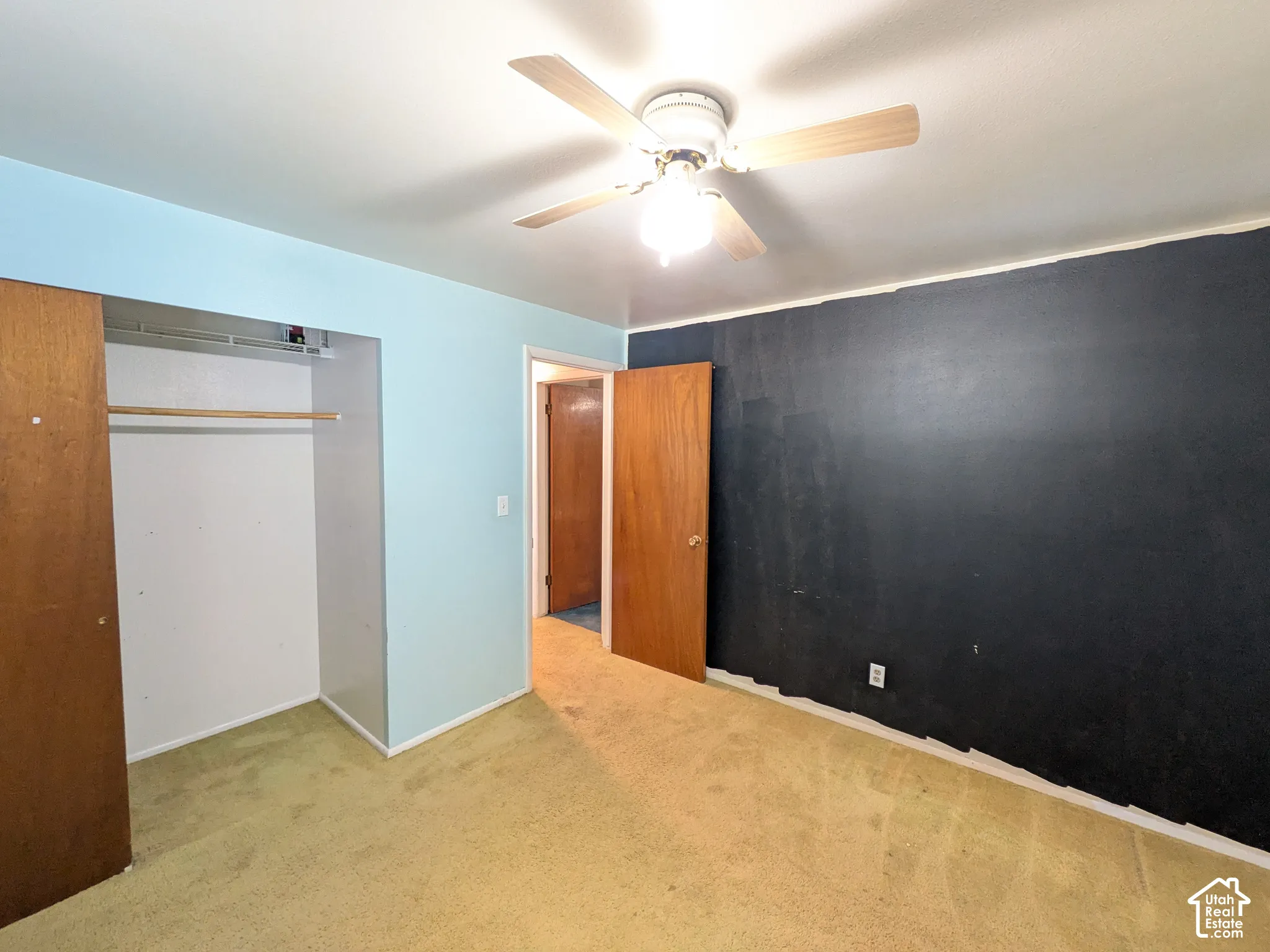 Room featuring wall-to-wall carpeting, a ceiling fan with integrated lighting, and a closet with wood-finish bi-fold doors