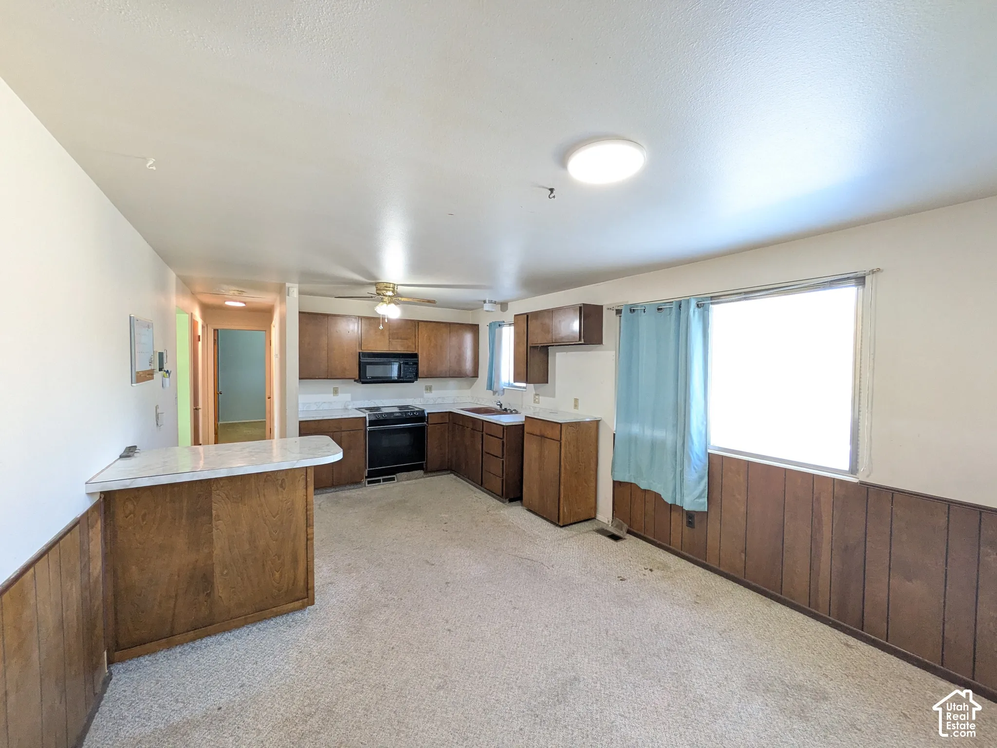 Kitchen featuring wood-finish cabinetry, white countertops, a black range, and a built-in microwave