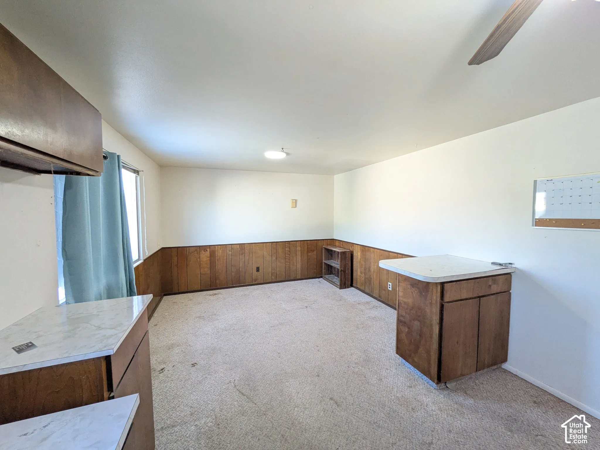 Built-in cabinetry with light-finish countertops, wood paneling, and a ceiling fan