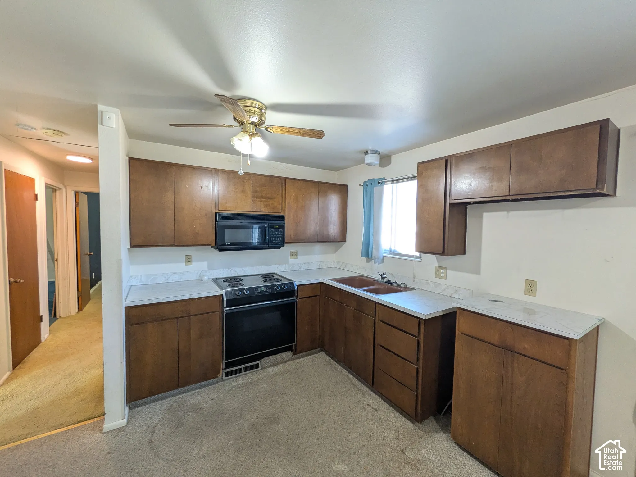 Kitchen featuring wood-finish cabinetry, white countertops, built-in microwave, and an electric range
