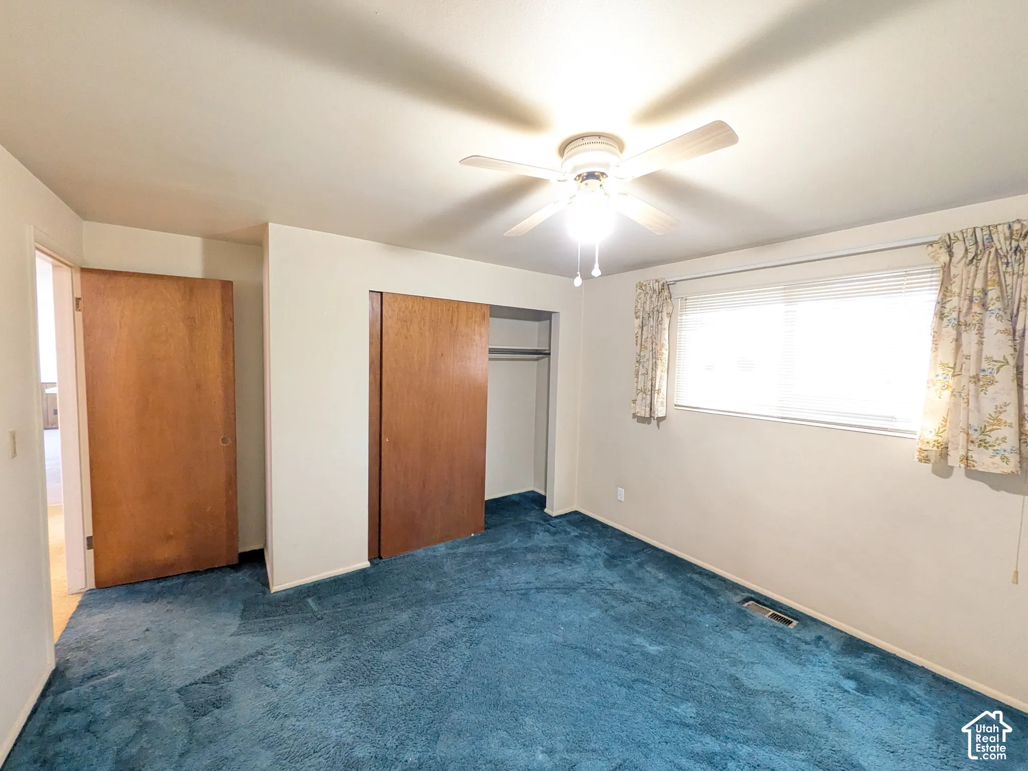 Ceiling fan with integrated lighting, wood-finish interior doors, sliding wood-finish closet doors, and light-filtering window treatments