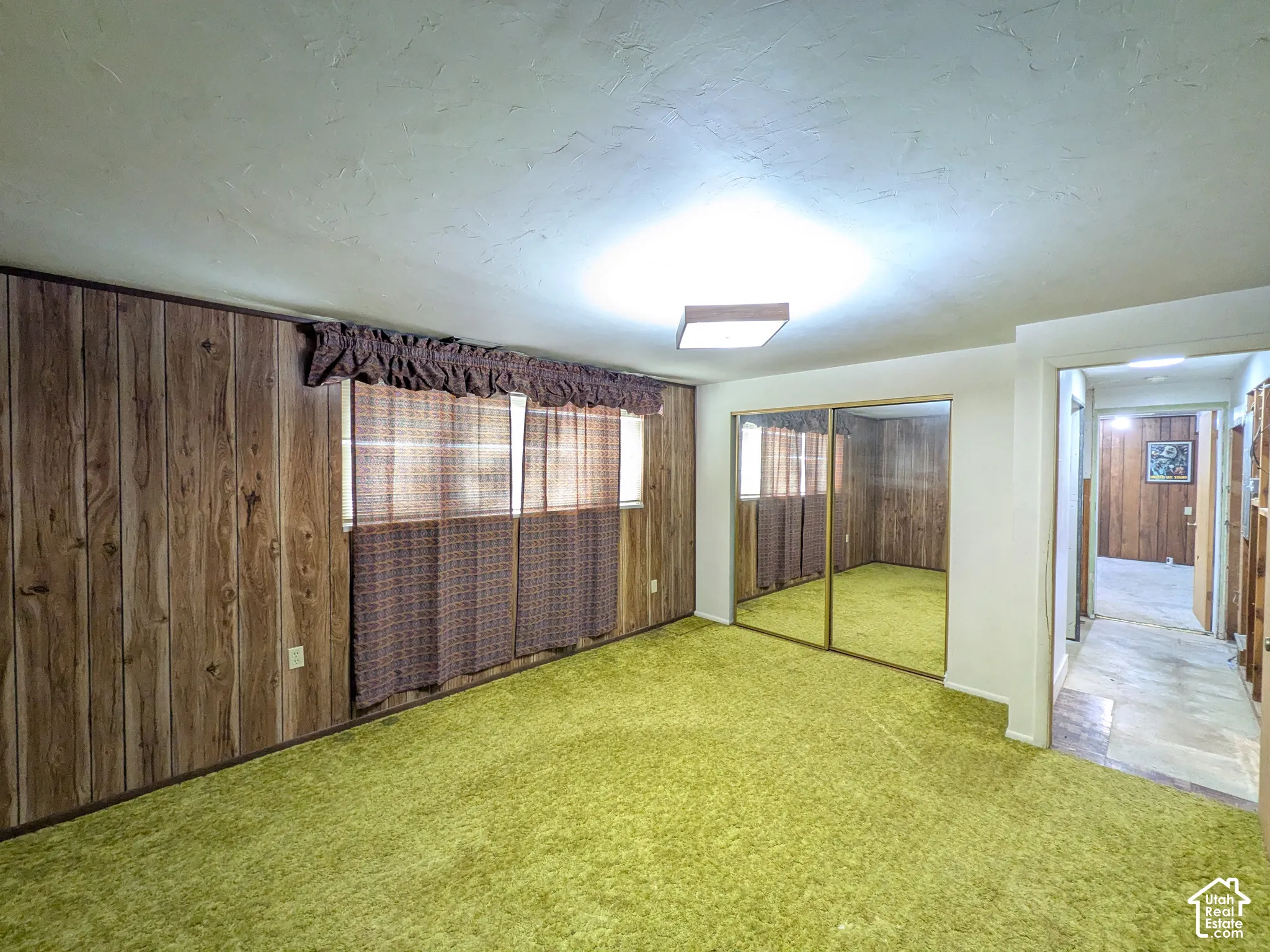 Wood-finish wall paneling, full-height mirrored closet doors, and textured ceilings