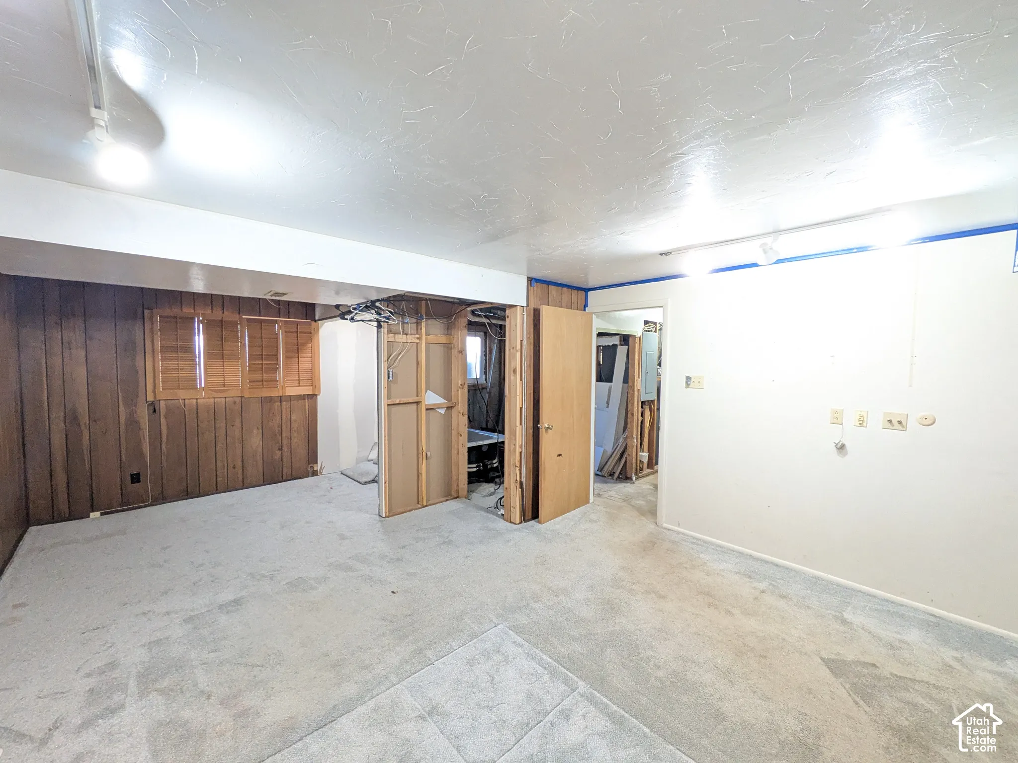Wall-to-wall carpeting and wood-paneled accent wall with integrated window shutters