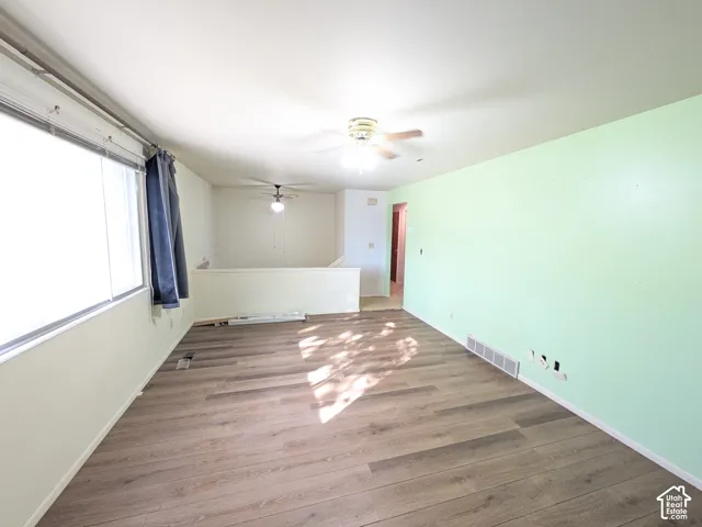 Wood-finish flooring, overhead ceiling fans, and a partial wall with open space