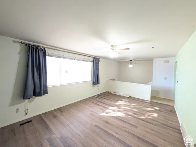 Wood-finish flooring, large window, ceiling fan, and a half-wall partition