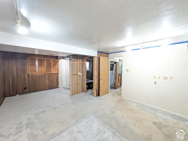 Wall-to-wall carpeting and wood-paneled accent wall with integrated window shutters