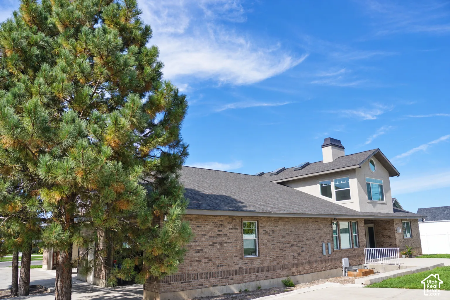 Brick exterior with a gray shingle roof, complemented by a stucco-clad upper level featuring an arched window