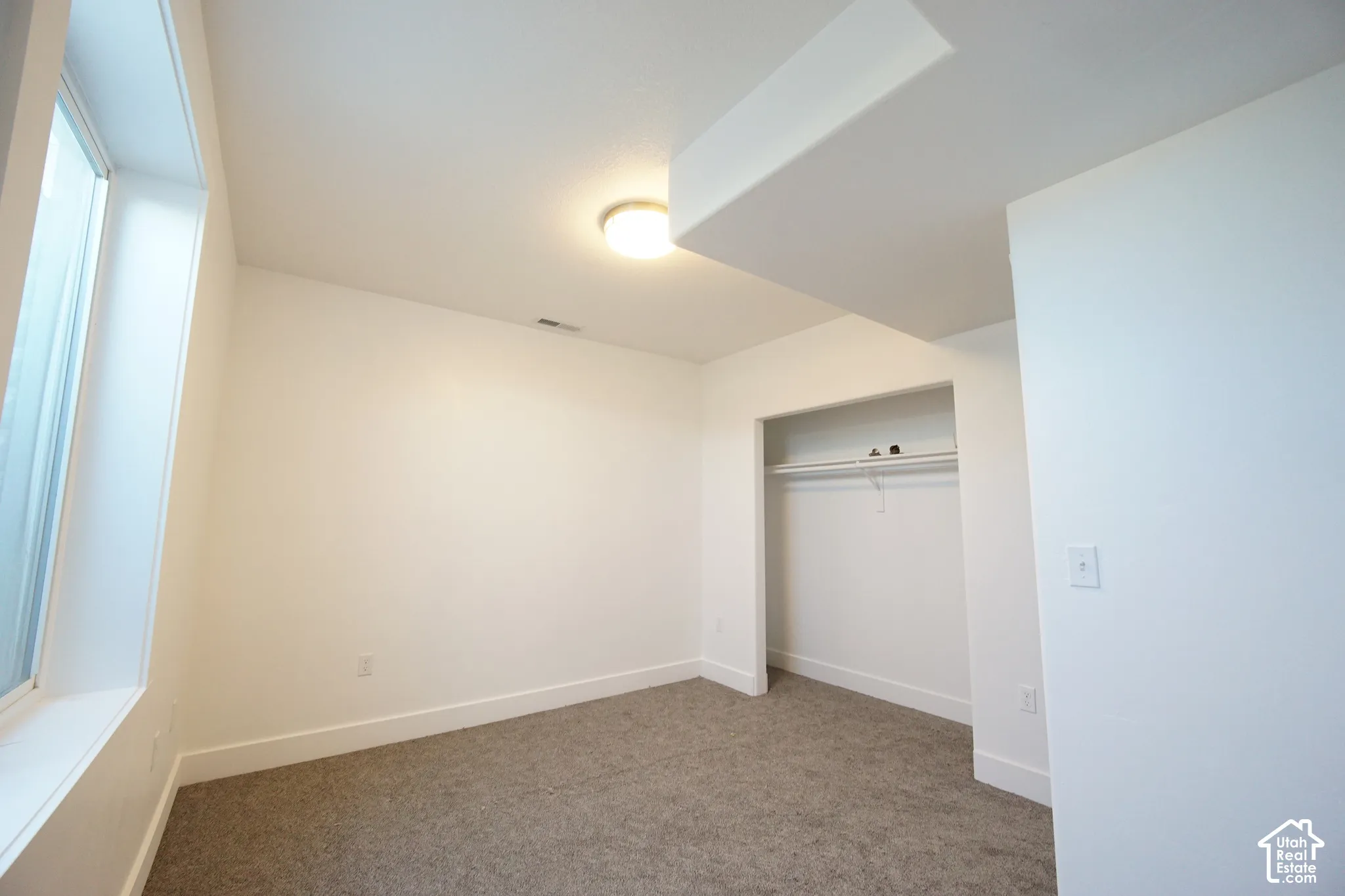 Recessed closet with built-in shelving, overhead lighting, and carpet flooring
