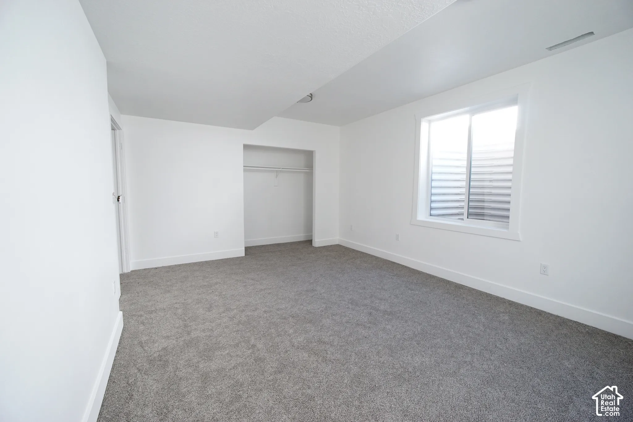 Recessed window, built-in closet with hanging rod, and light gray carpeting