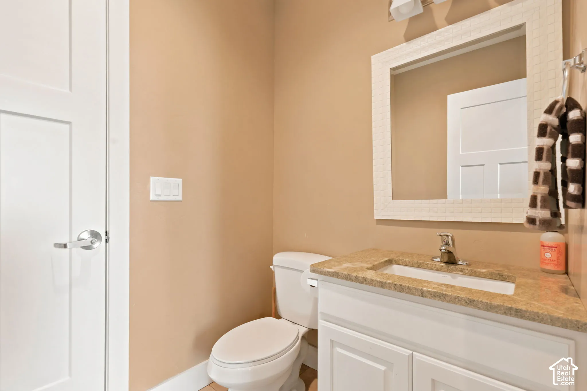 Bathroom vanity with a granite-style countertop, undermount sink, and chrome faucet