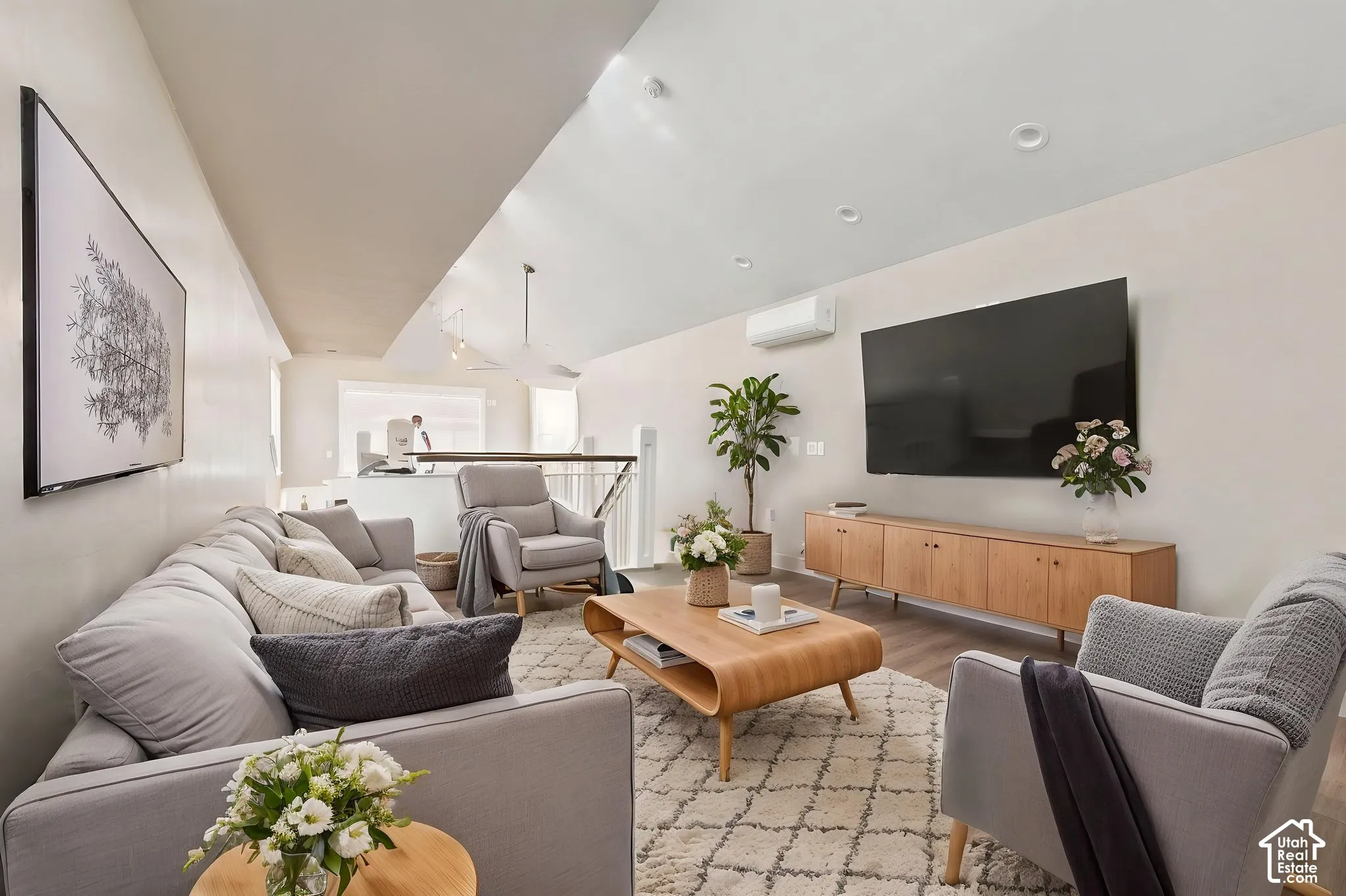 Light-filled living area featuring vaulted ceilings, recessed lighting, and wood-finish   Digitally staged.
