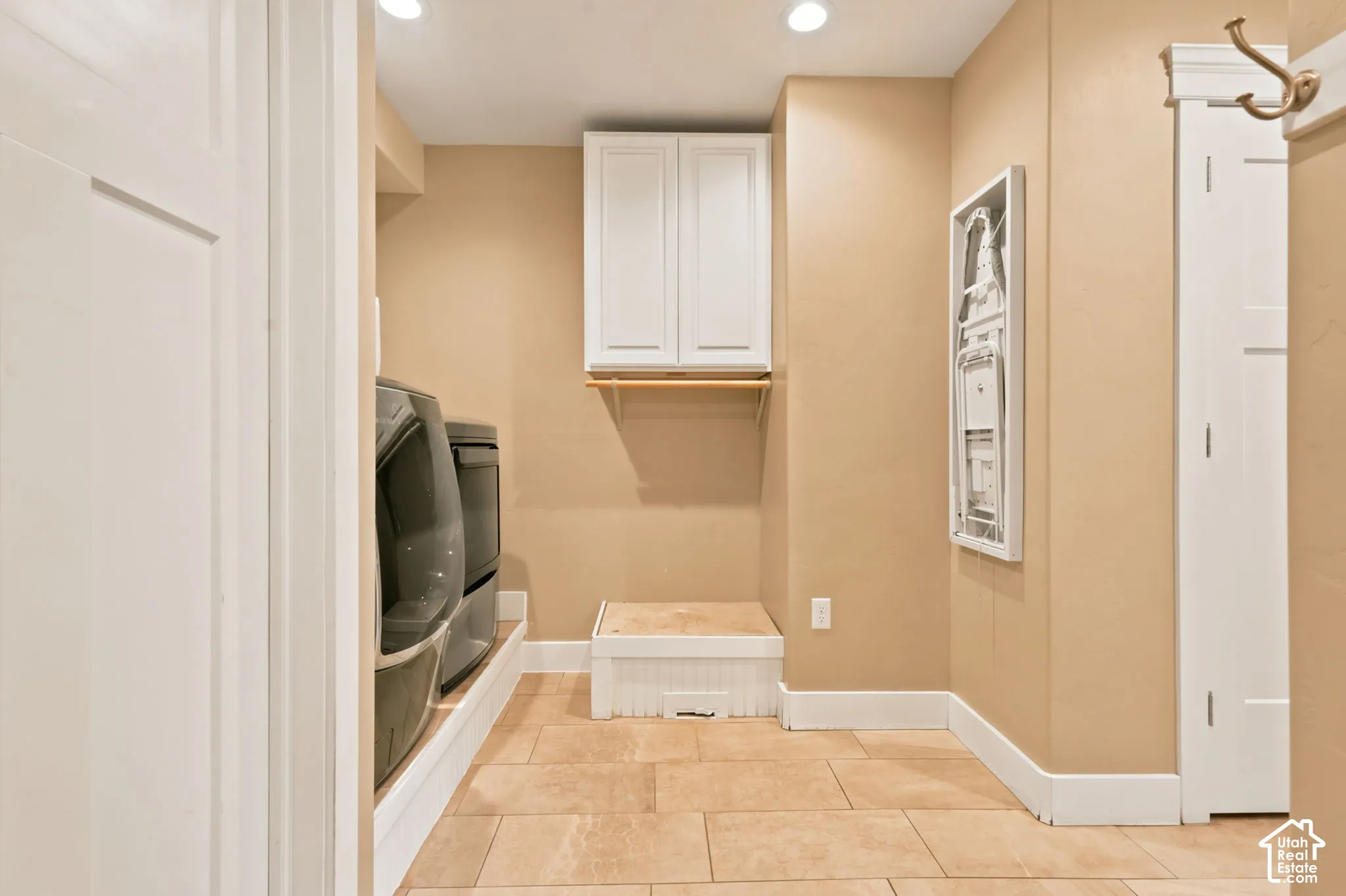 Utility space featuring tile flooring, recessed lighting, white cabinetry, and a wooden hanging rod