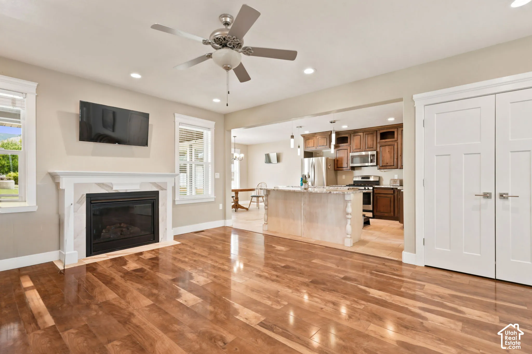 Open concept living area featuring wood-finish flooring, a fireplace with a white mantel, and recessed lighting