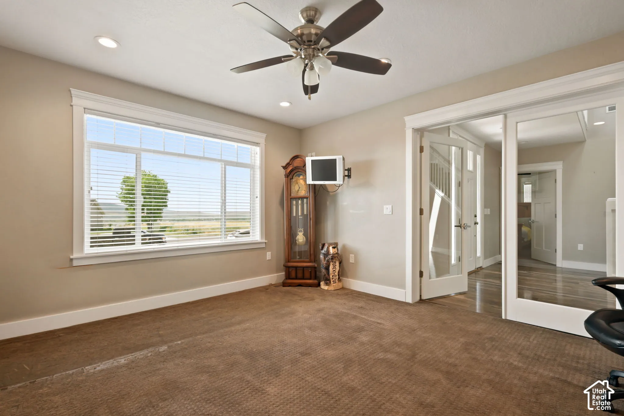 Carpeted room featuring a multi-pane window, white baseboards, and neutral wall tones