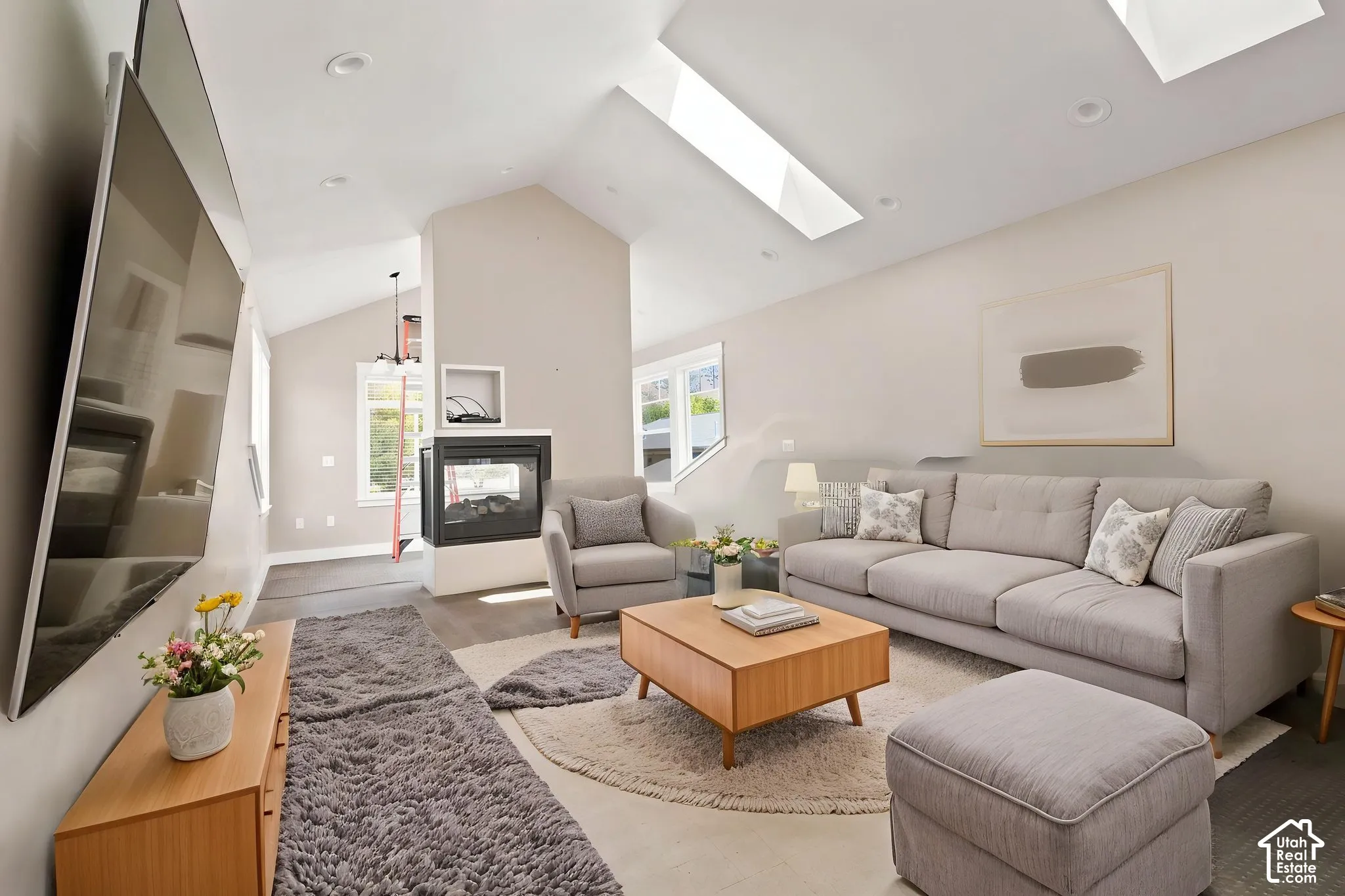 Living area featuring vaulted ceilings, recessed lighting, and multiple   Digitally staged.