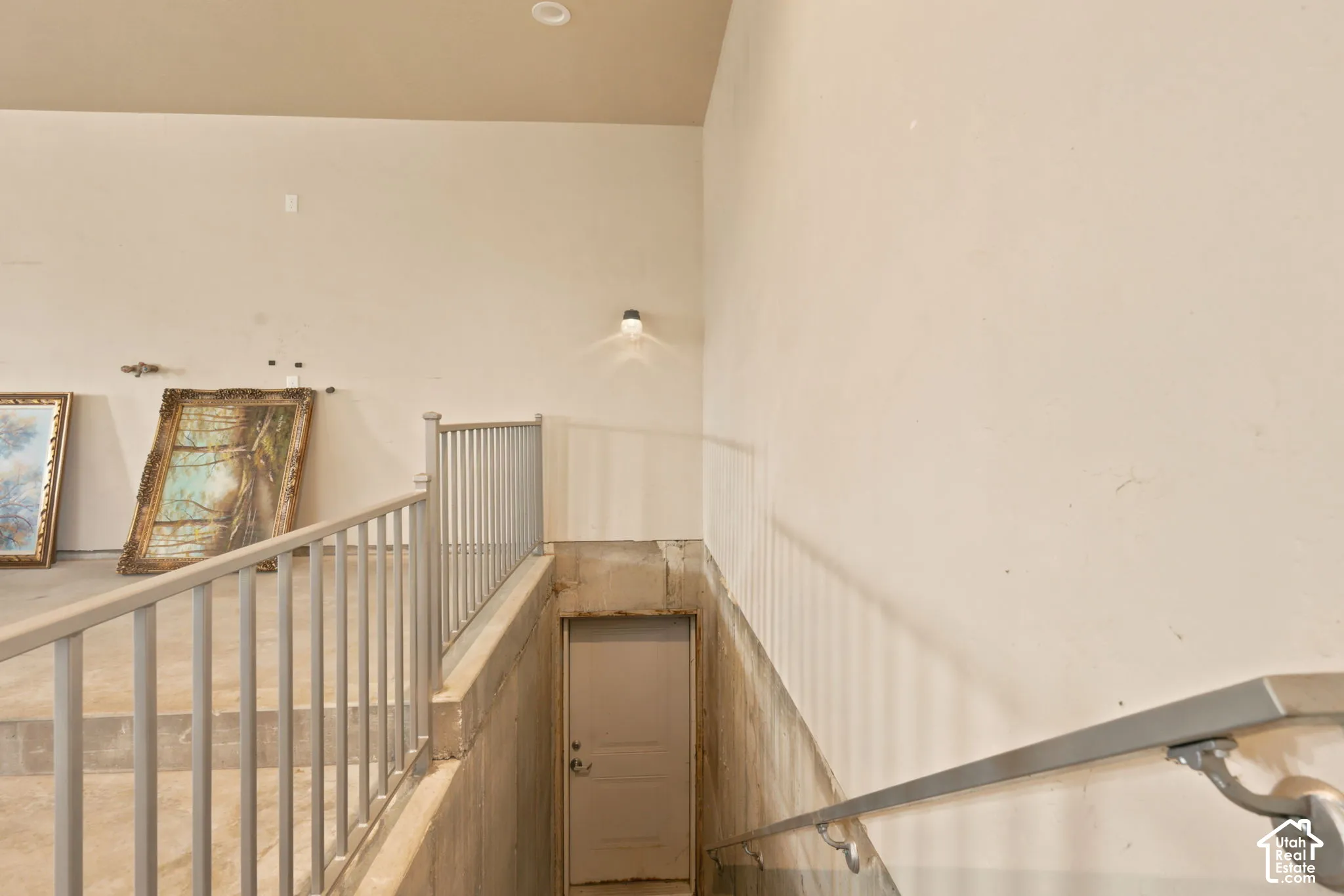 Staircase featuring light-toned walls, metal railings, and an enclosed doorway