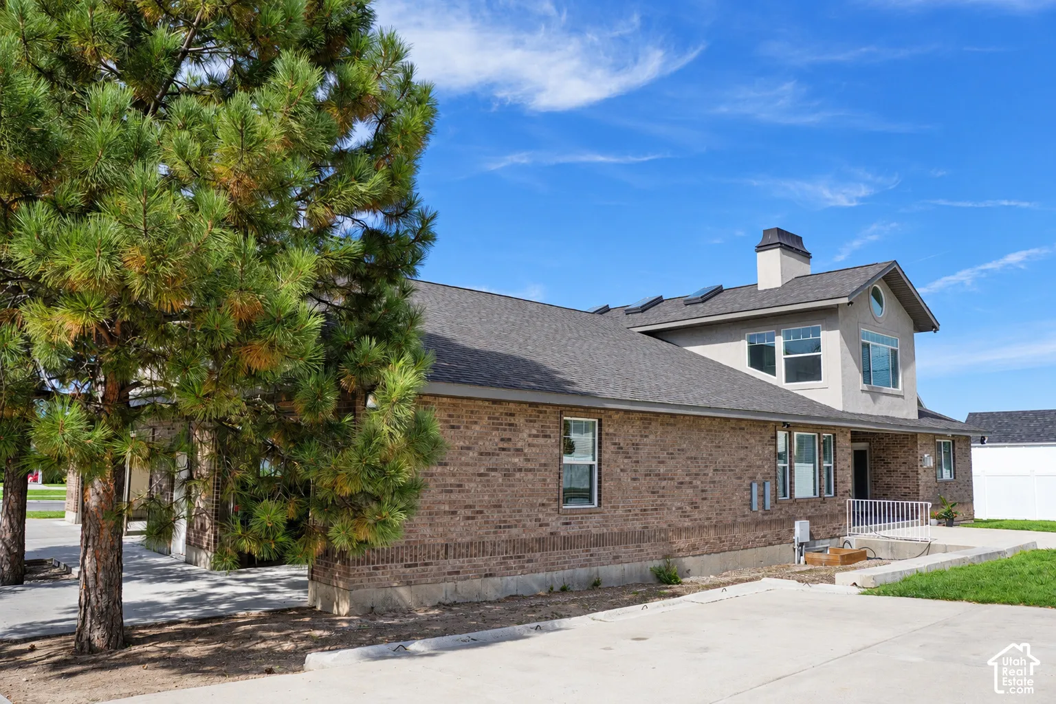 Brick exterior with a stucco accent, multiple windows, and a dark shingle roof