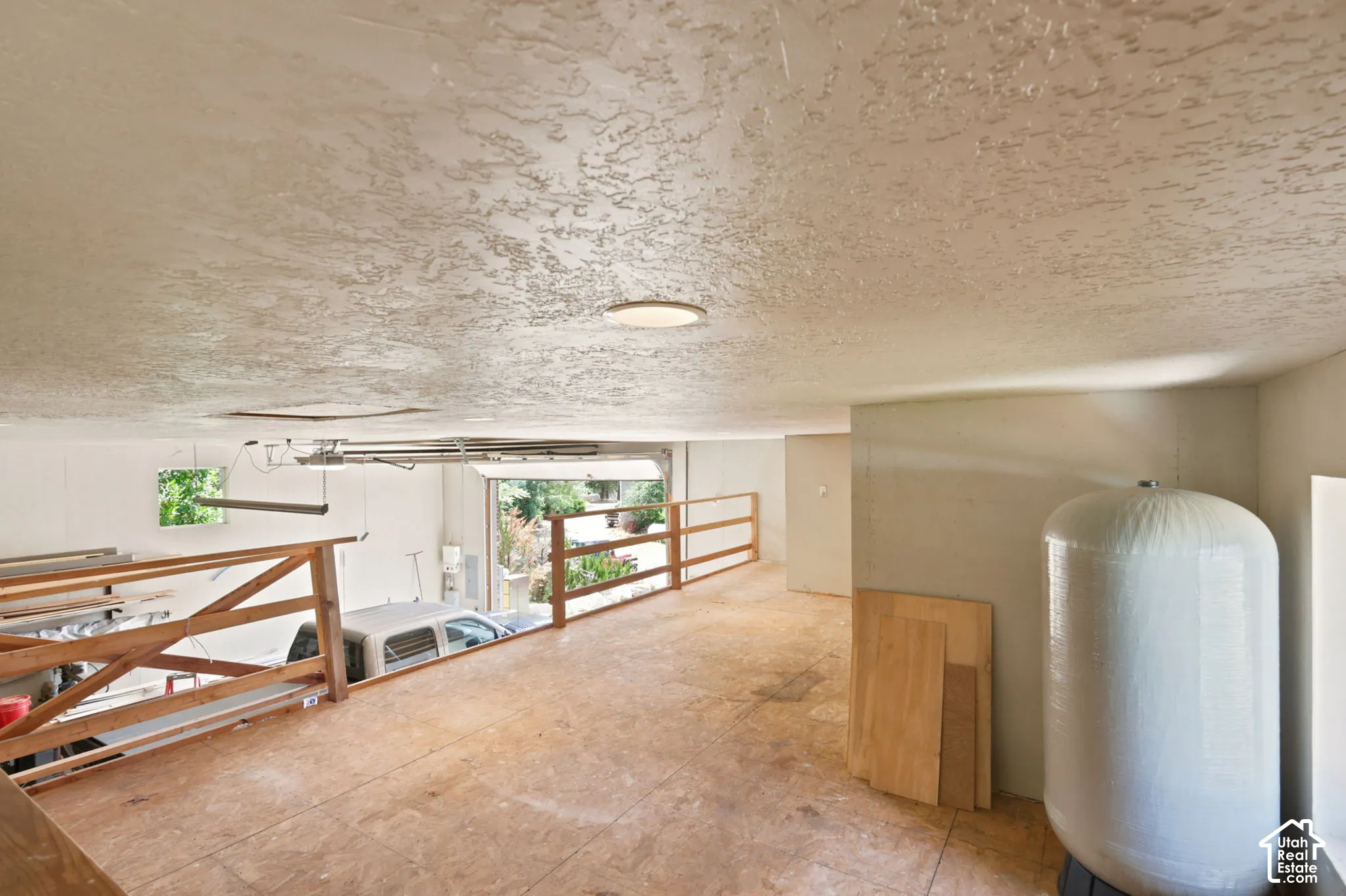 Unfinished loft area featuring plywood flooring and a textured ceiling