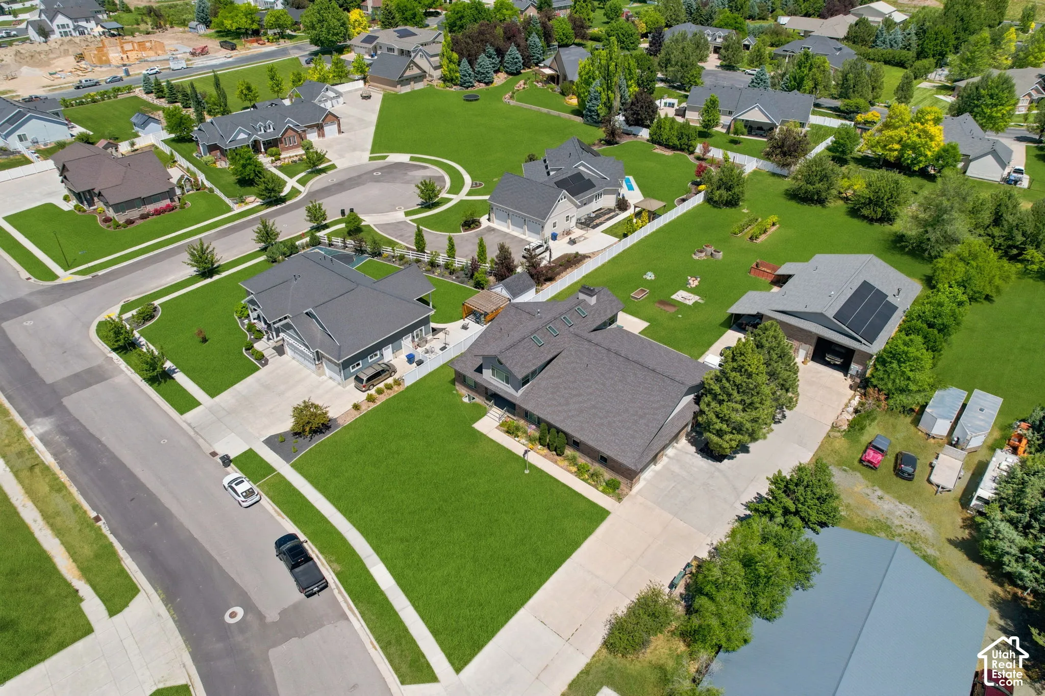 Spacious property featuring a large concrete driveway, expansive green lawn, and a multi-car garage
