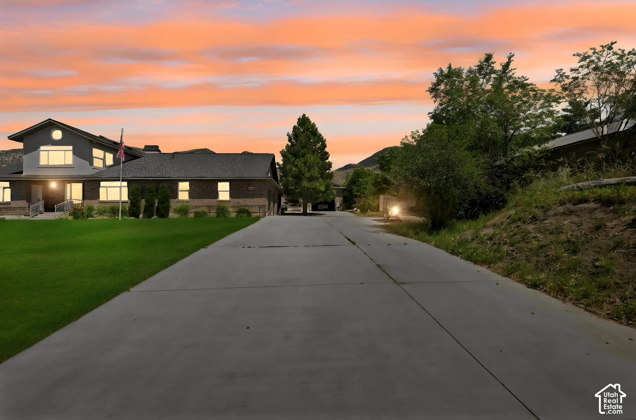 Expansive concrete driveway leading to a multi-level residence featuring brick and siding exterior construction  Digitally staged.