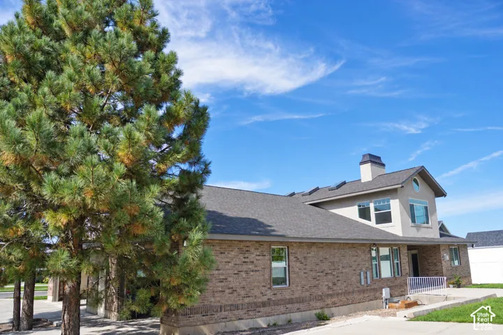 Brick exterior with a gray shingle roof, complemented by a stucco-clad upper level featuring an arched window