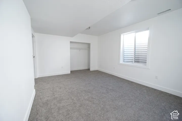Recessed window, built-in closet with hanging rod, and light gray carpeting