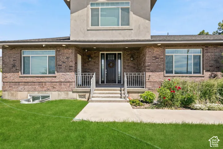 Brick and stucco exterior featuring multiple windows and a covered porch