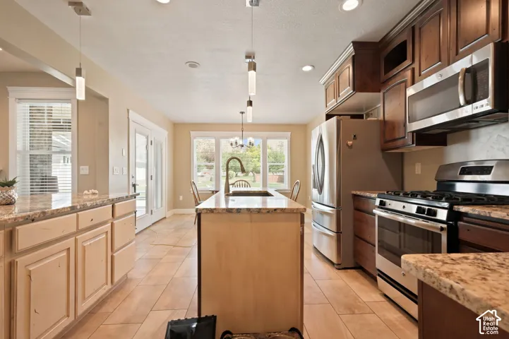 Spacious kitchen featuring an island with an undermount sink and gooseneck faucet, light-toned cabinetry, stainless steel appliances, and tile flooring