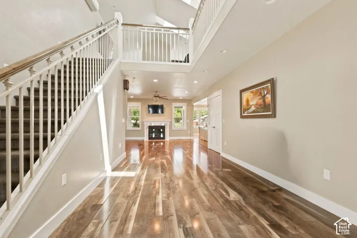 Spacious interior featuring wood-finish flooring, a grand staircase with white balusters, and recessed lighting