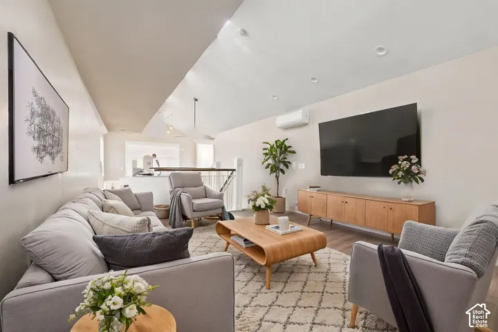 Light-filled living area featuring vaulted ceilings, recessed lighting, and wood-finish   Digitally staged.