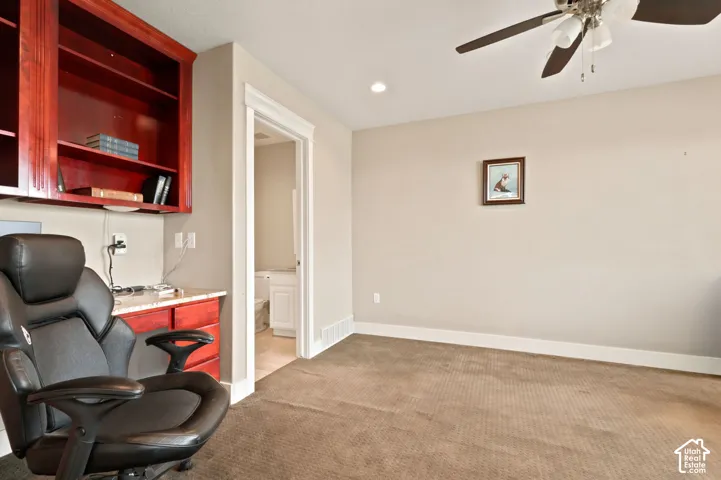 Bedroom with dedicated workspace featuring built-in cherry-toned cabinetry and shelving, a light-toned countertop, and recessed lighting