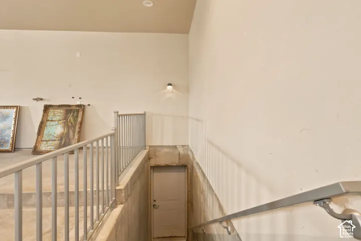 Staircase featuring light-toned walls, metal railings, and an enclosed doorway