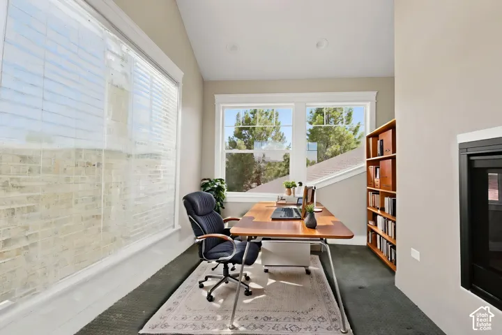 Bright interior space featuring multiple windows, sloped ceiling, recessed lighting, and a built-in fireplace with a black surround  Digitally staged.