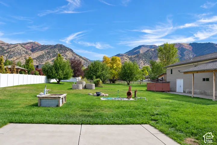 Expansive green lawn with mountain scenery, a white privacy fence, and a patio area