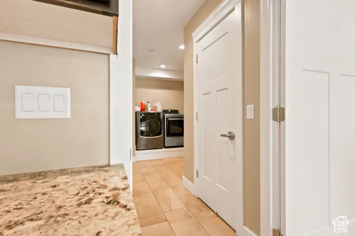 Dedicated laundry area featuring tile flooring, neutral wall tones, modern doors with brushed nickel hardware, and recessed lighting