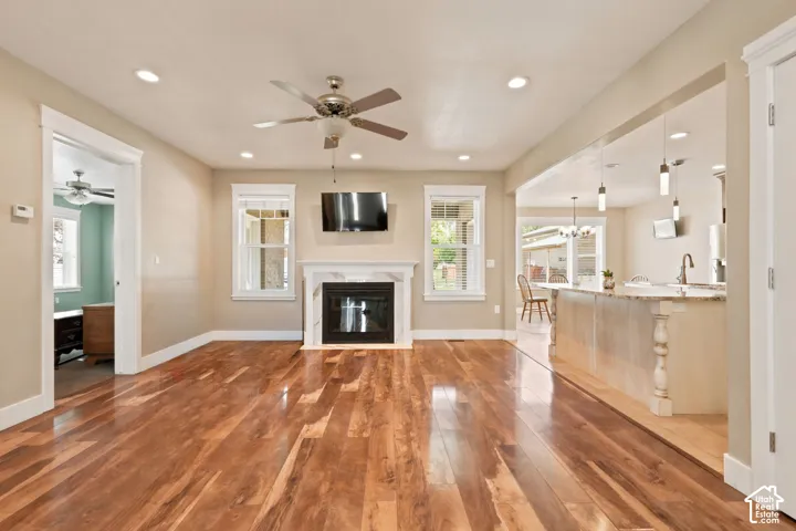 Spacious living area featuring wood-finish flooring, a fireplace with a white mantel, and recessed lighting