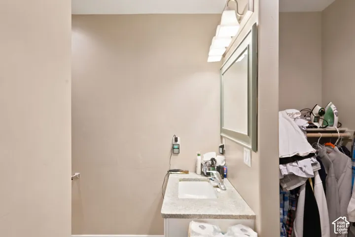 Vanity area featuring a light-toned countertop with an integrated sink, a large framed mirror, and a five-light fixture  Digitally staged.