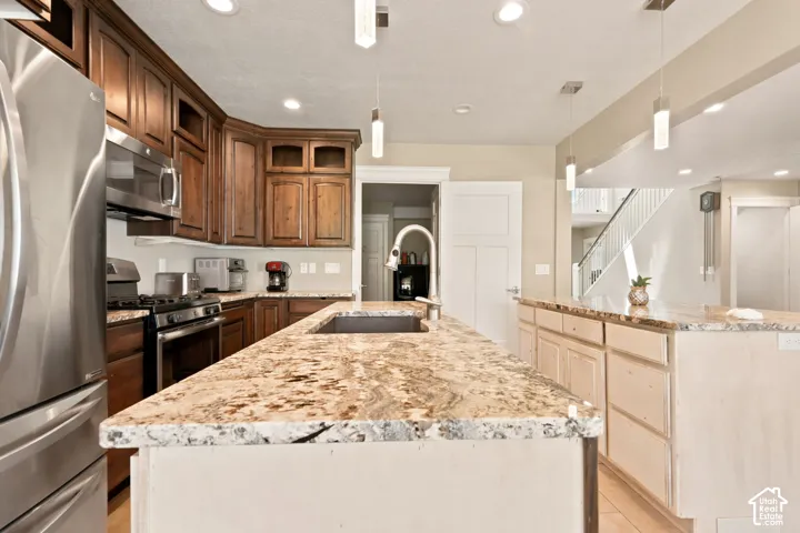 Kitchen featuring dual islands with stone countertops, stainless steel appliances, dark wood cabinetry, and recessed lighting
