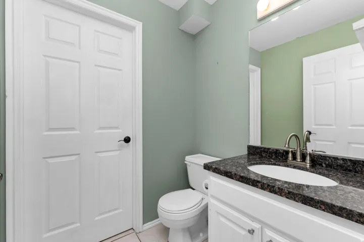 Half-Bath featuring a white vanity with dark countertop, undermount sink, and brushed nickel faucet