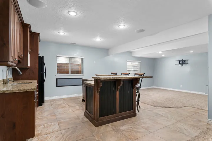 Built-in wet bar with dark wood cabinetry and stone-finish countertops