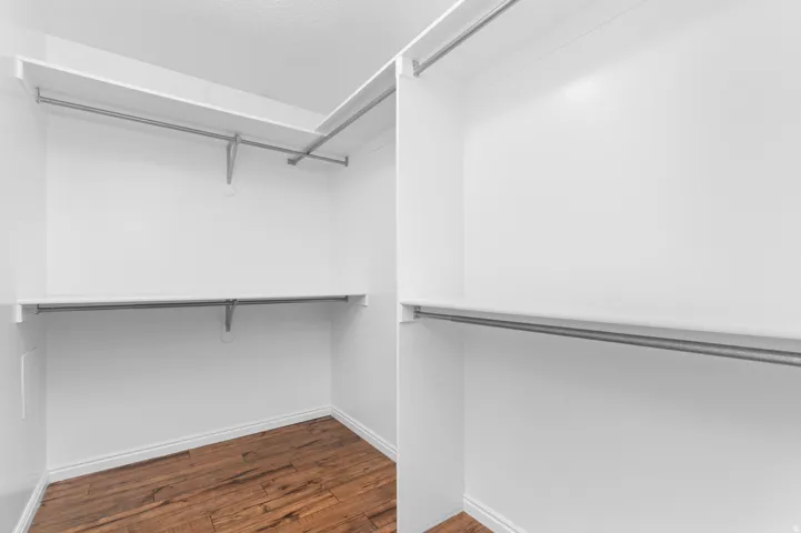 Primary Bedroom Suite Walk-in closet with wood-finish flooring, white walls, built-in shelving, and metal hanging rods