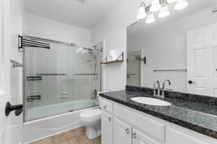 White vanity with dark stone countertop, undermount sink, and brushed nickel faucet