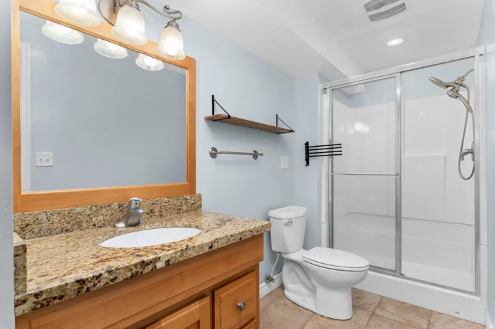 Vanity with a granite-style countertop, a single basin sink, and wood cabinetry