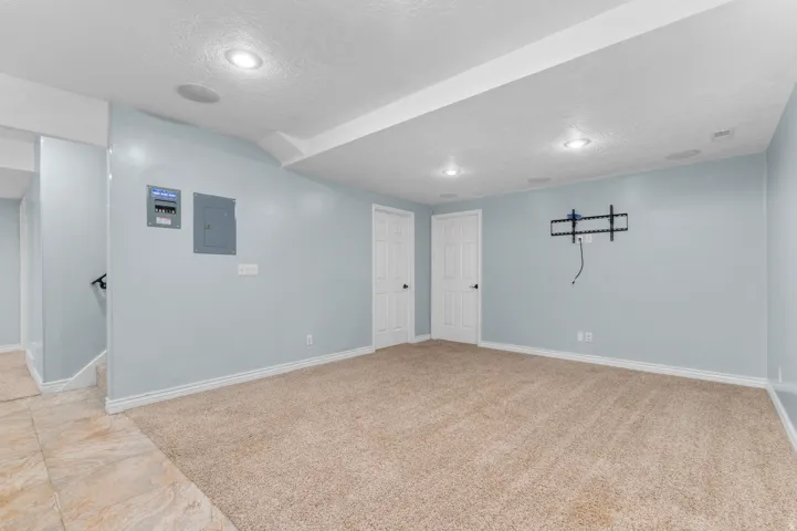 Carpeted room with recessed lighting, two white panel doors, and a wall-mounted bracket