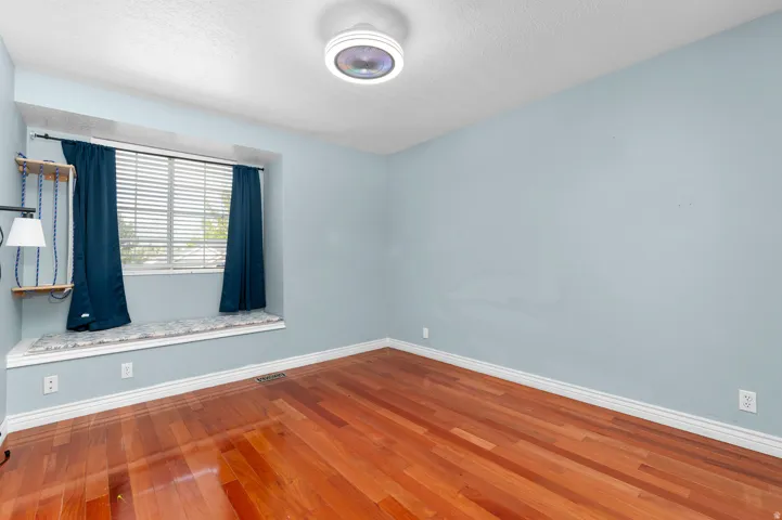 Hardwood flooring throughout, recessed window with built-in bench, and a ceiling-mounted light fixture