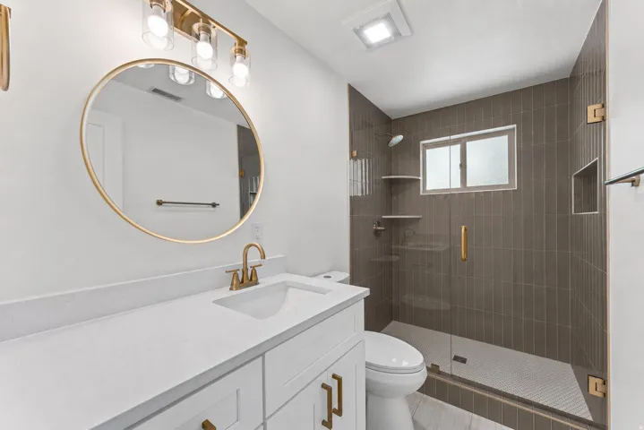 Contemporary bathroom featuring a spacious vanity with a white countertop and gold-toned fixtures