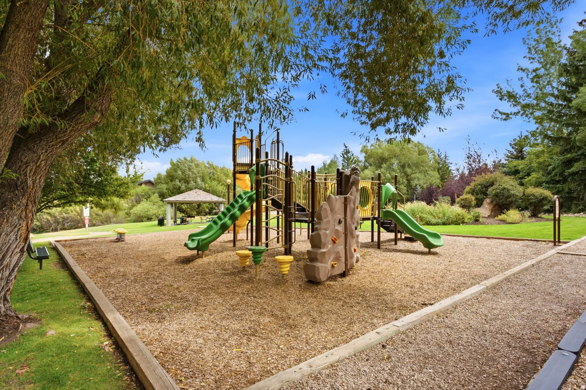 Community playground featuring multiple slides, climbing structures, and a wood chip base