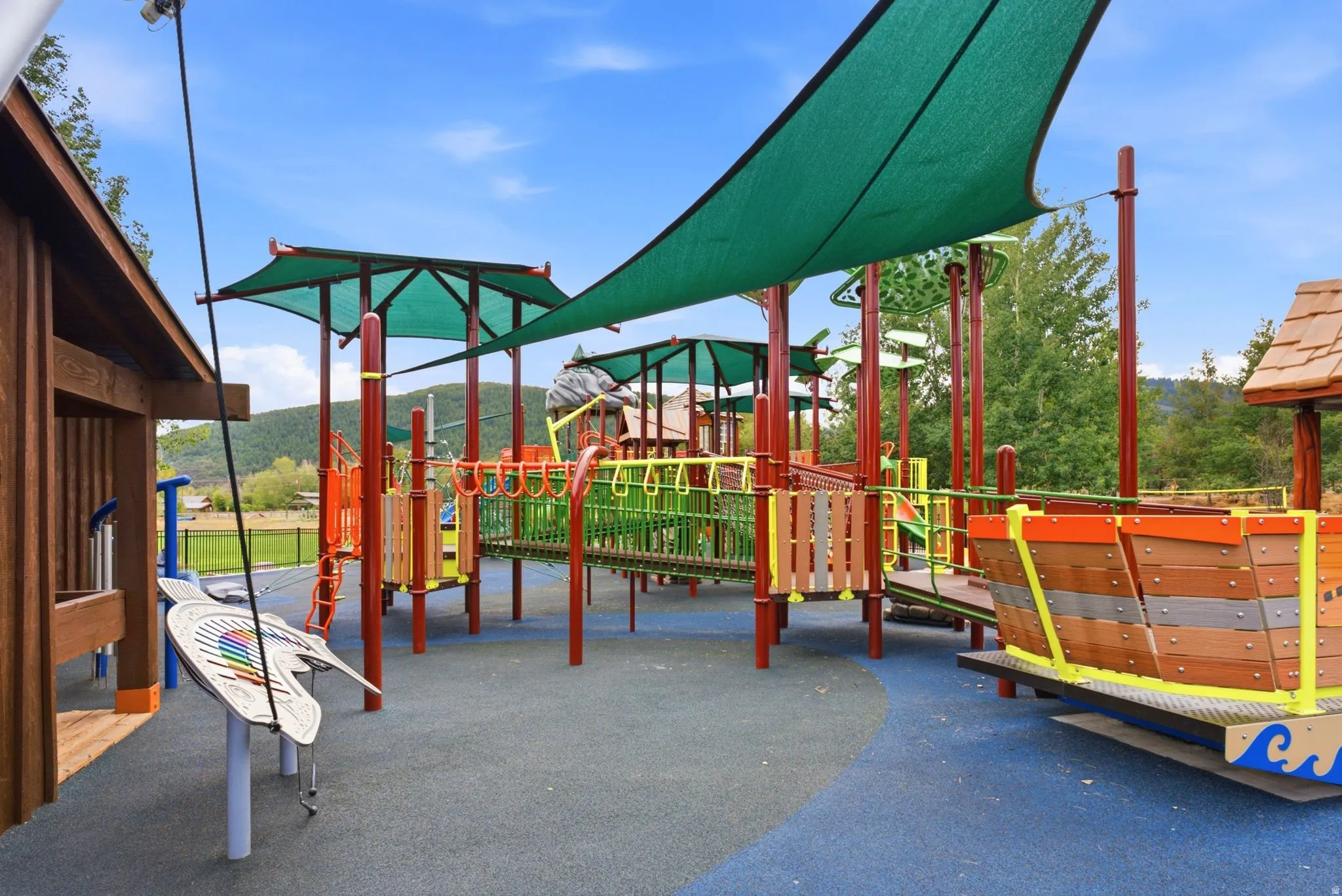 Recreational playground area featuring a composite structure, shade canopies, and a soft-fall surface