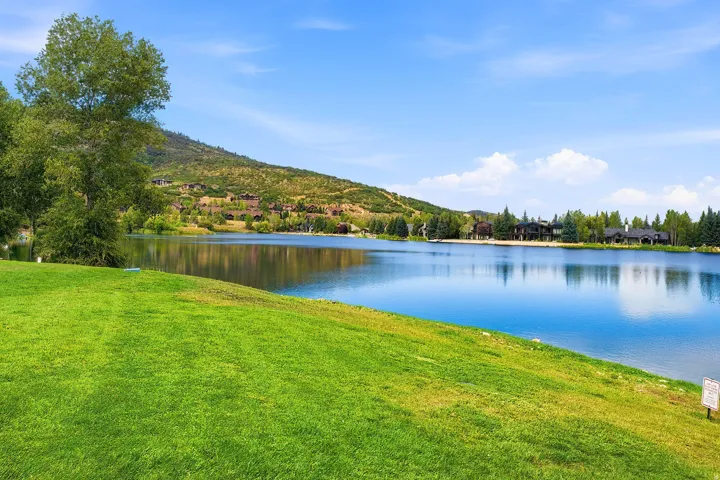 Lush green lawn with mature trees, offering extensive lake frontage with mountain backdrop